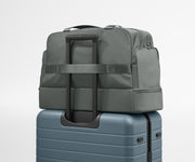 Gray backpack on top of a blue suitcase against a light gray background