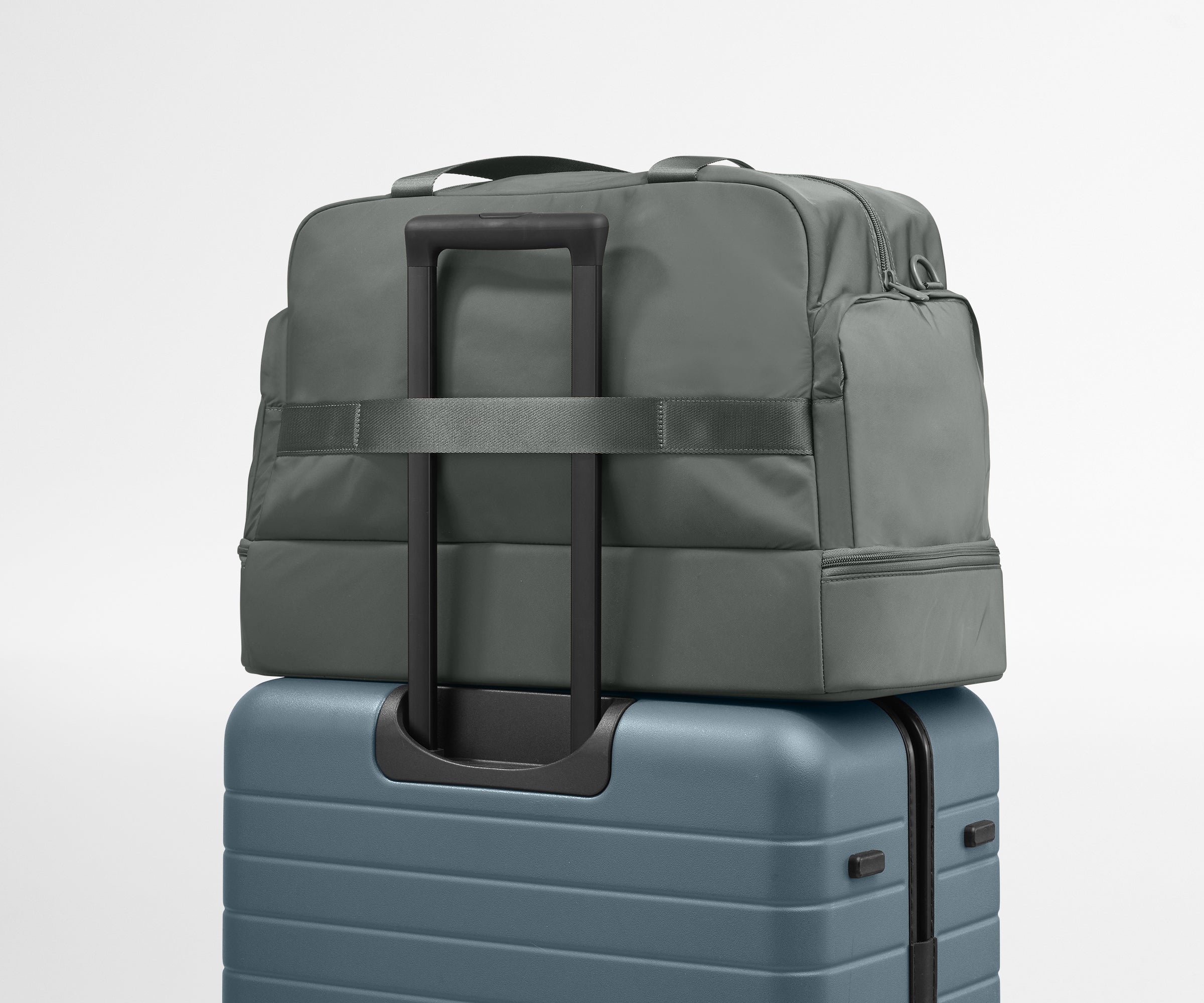 Gray backpack on top of a blue suitcase against a light gray background