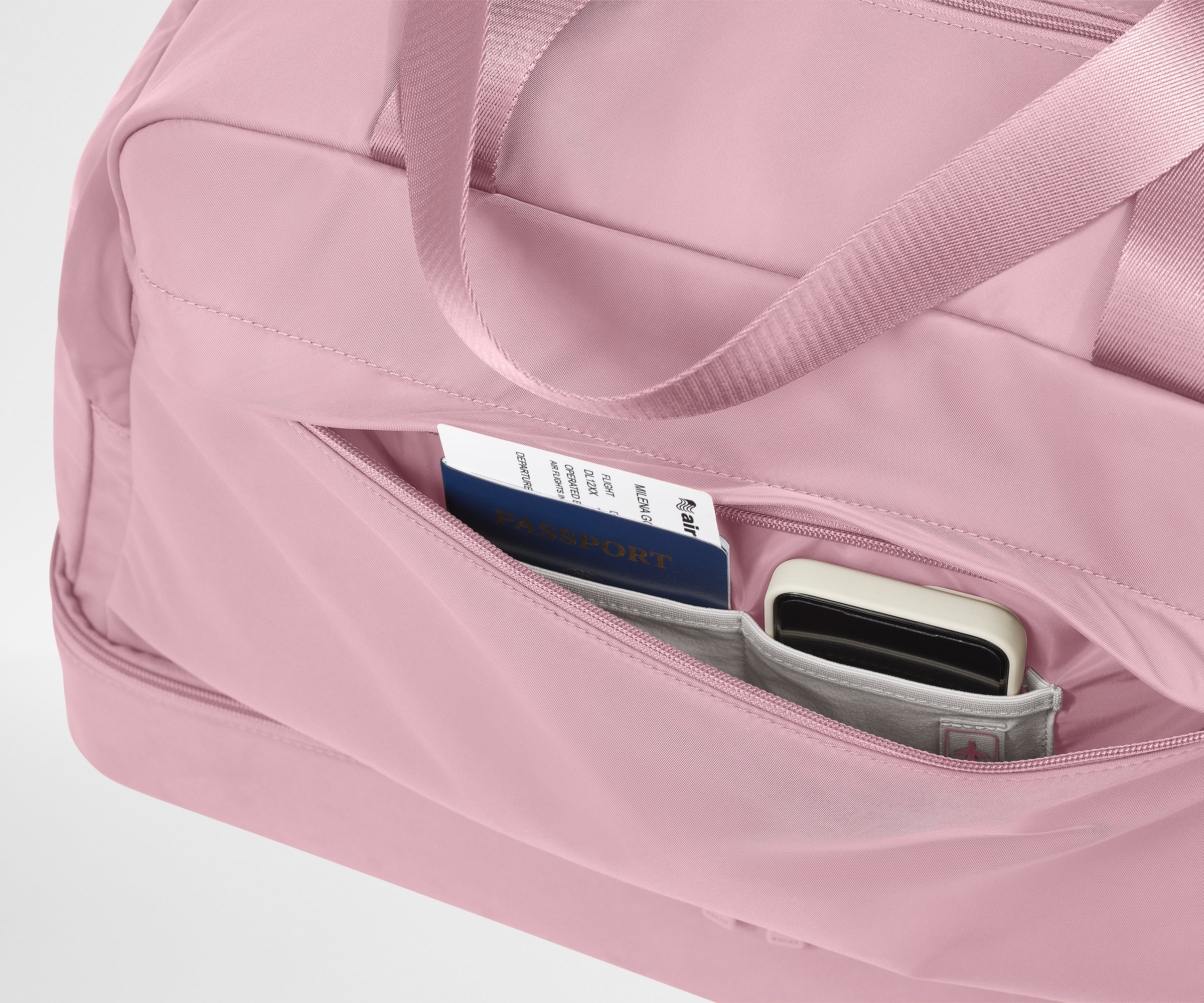 Pink travel bag with a compartment containing a passport and wallet on a light gray background