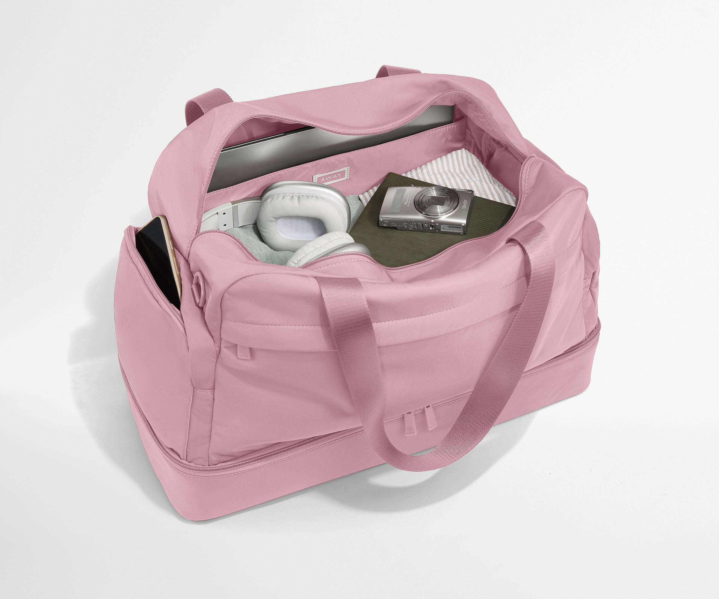 Pink duffel bag with items inside on a light gray background