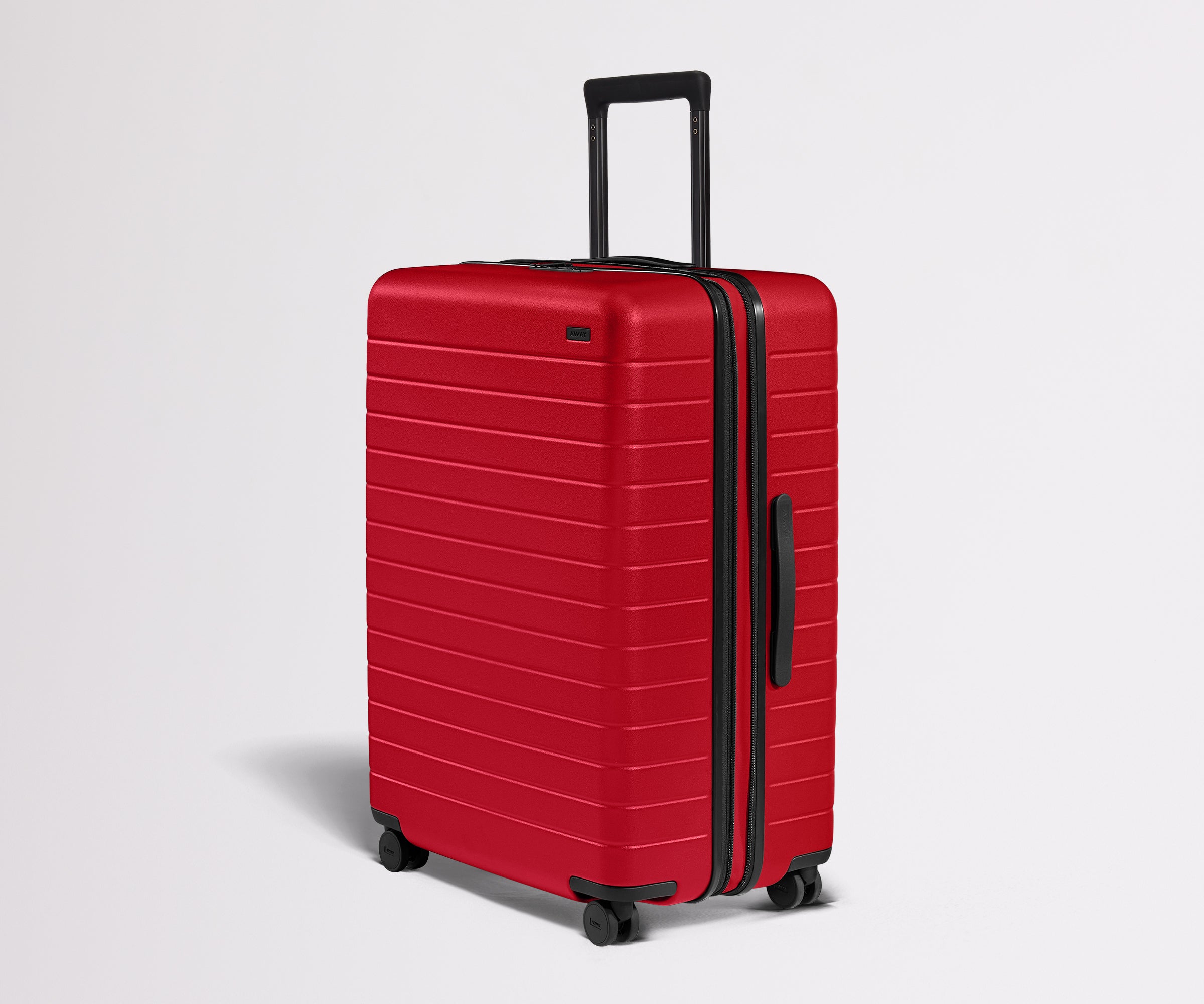 Red suitcase with black handle and wheels on a light gray background