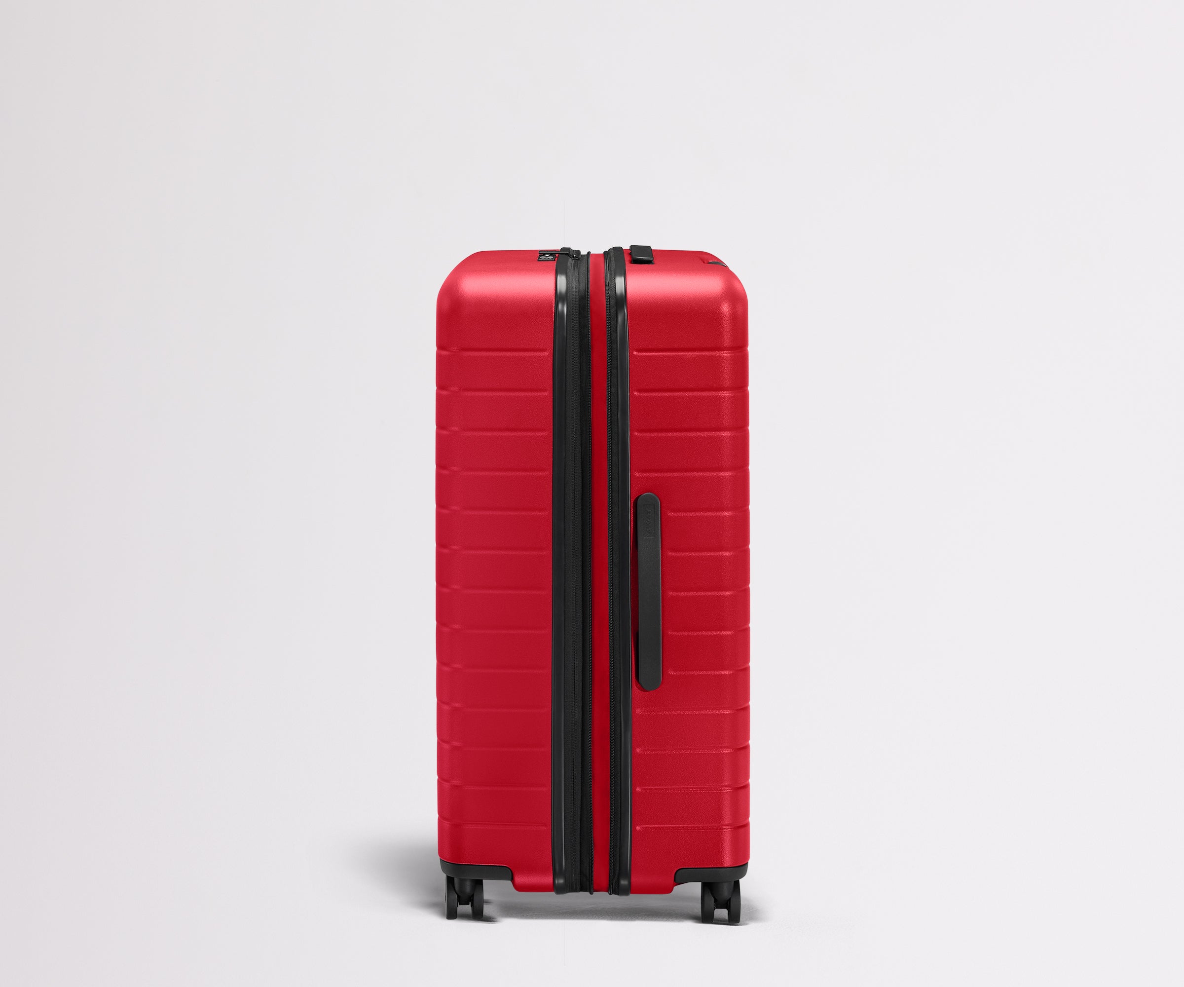 Red suitcase with black handle and wheels on a light gray background