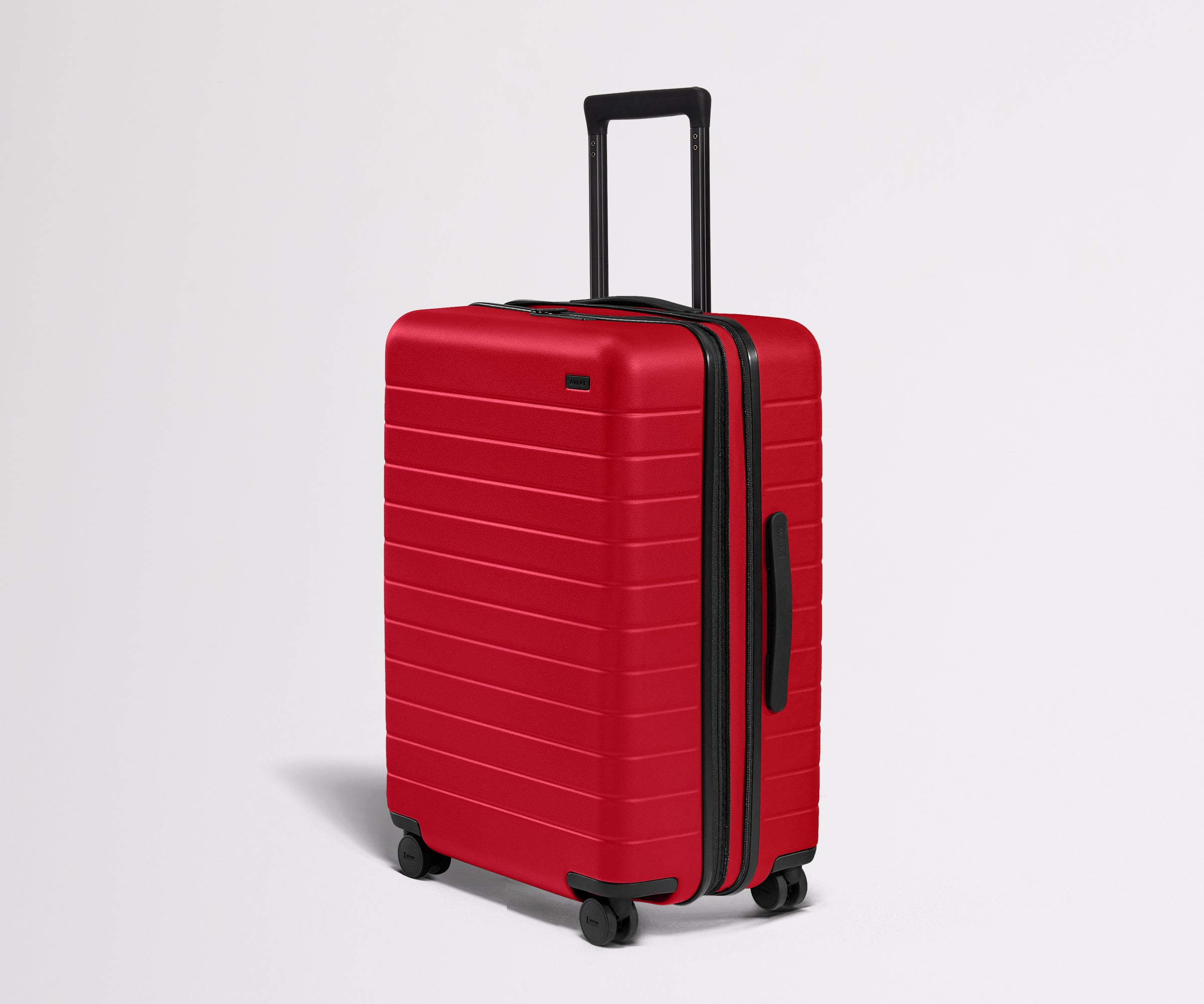 Red suitcase with black handle and wheels on a light gray background