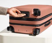 The Carry-On Flex suitcase in Clay Pink shown from below highlighting the underside grab handle