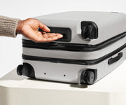The Bigger Carry-On Flex suitcase in Cloud Gray shown from below highlighting the underside grab handle