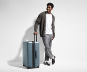 6'1" person walking with The Large Flex suitcase