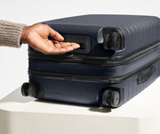 The Bigger Carry-On Flex suitcase in Navy Blue shown from below highlighting the underside grab handle