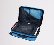 The Bigger Carry-On Flex suitcase in Splash Blue shown open on its side and packed with Away's packing organizers to show capacity and the interior compression system, designed to help you pack more in