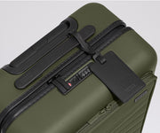 The Front Pocket Carry-On suitcase in Olive Green shown shown from above highlighting TSA-approved combination lock and black leather luggage tag