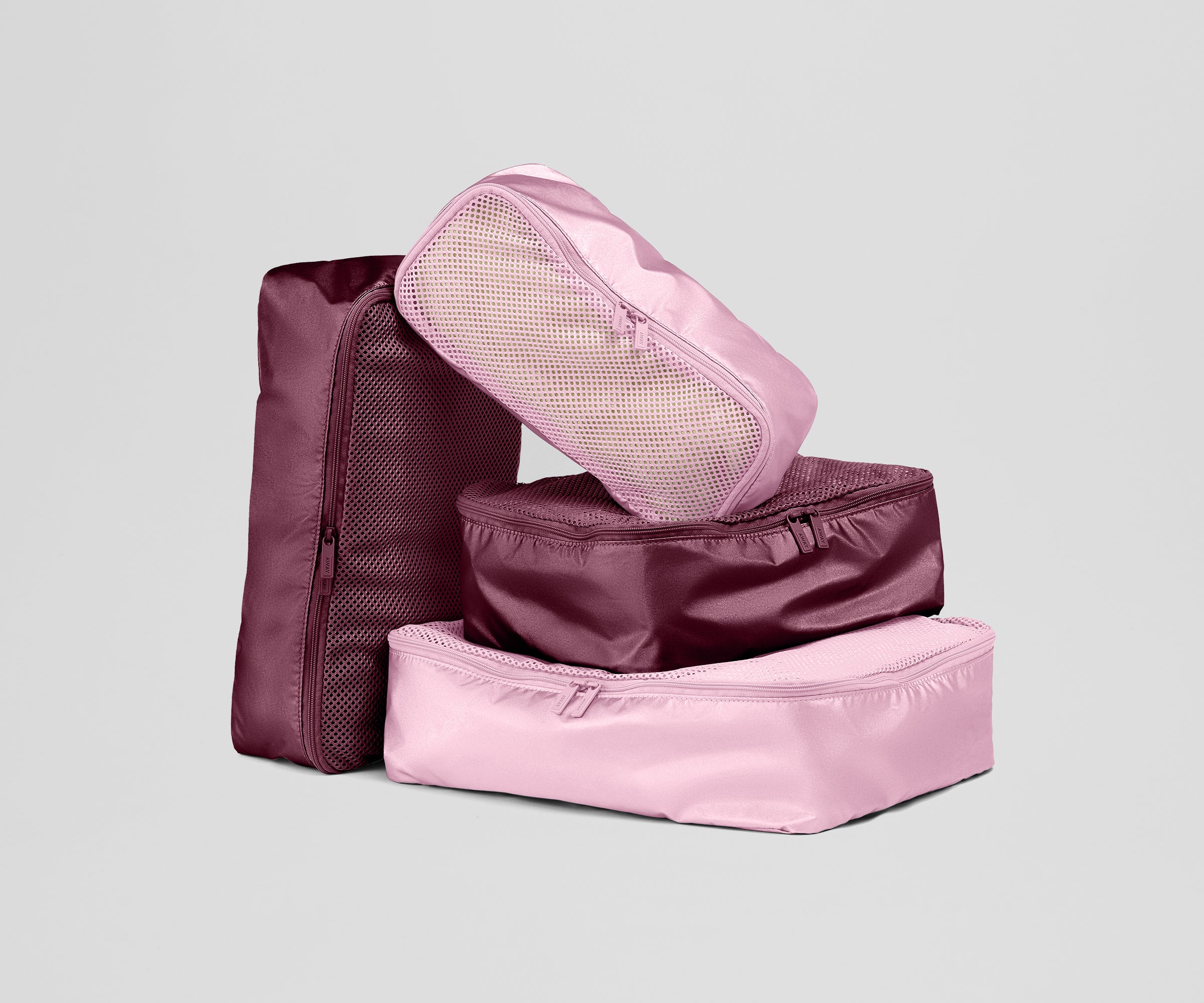 Set of pink and maroon packing cubes on a light gray background