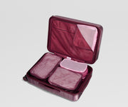 Maroon and pink travel packing cube set in a matching maroon suitcase