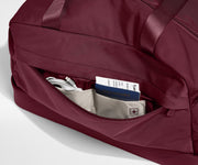 Maroon weekender with a pocket open, revealing travel documents and cables.