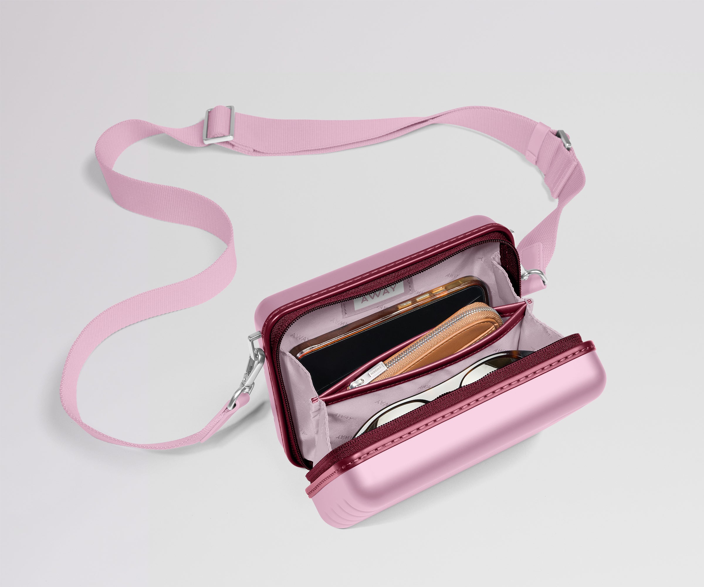 Pink crossbody bag with a strap on a light gray background