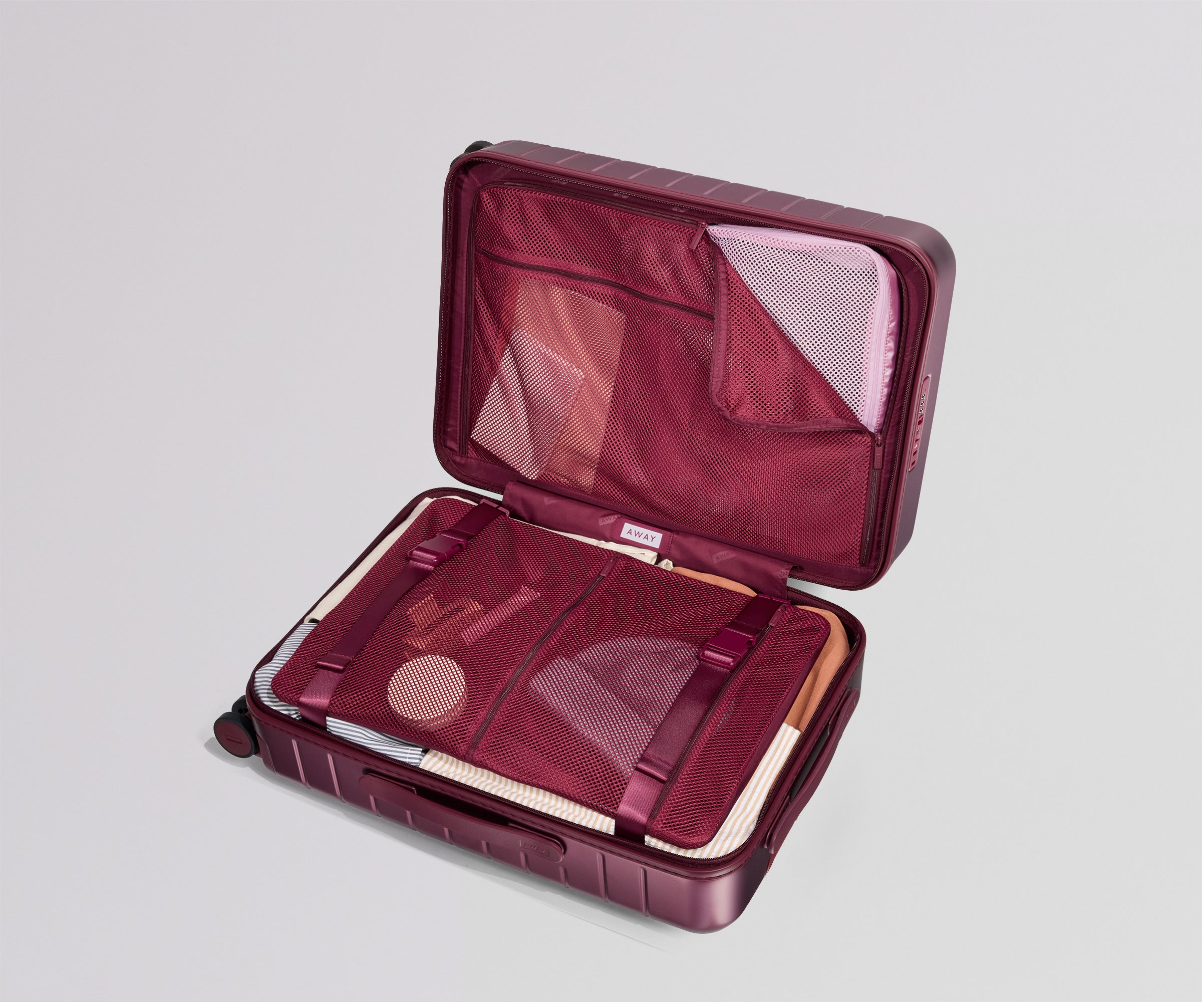 Open maroon travel case with mesh interior on a light gray background