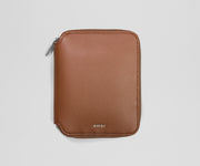 Brown leather jewelry organizer with 'AWAY' branding on a light gray background