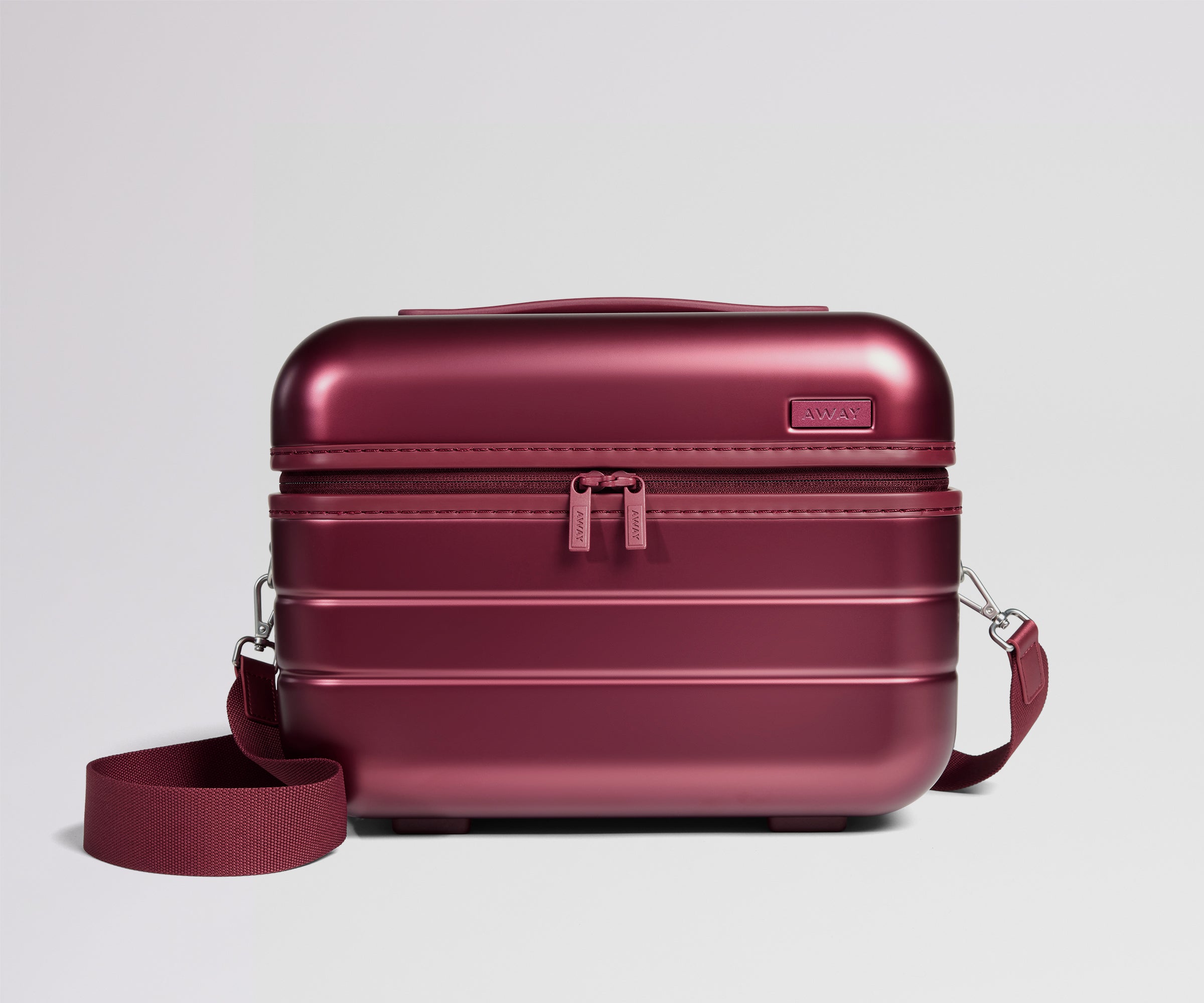 Red travel case with a strap on a light gray background