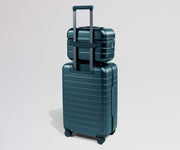 Teal suitcase with a smaller teal suitcase on top against a light gray background