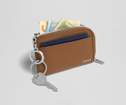 Brown wallet with keys and money on a light gray background