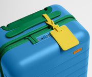The Kids Carry-On suitcase in Splash Blue shown shown from above highlighting TSA-approved combination lock and colorful silicone luggage tag