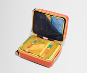 The Kids Carry-On suitcase in Poppy Orange shown open on its side and packed with Away's packing organizers to show capacity and the interior compression system, designed to help you pack more in