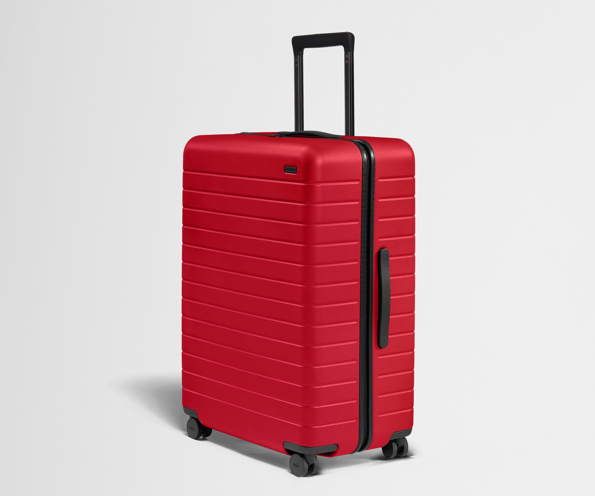 Red suitcase with black handle and wheels on a light gray background