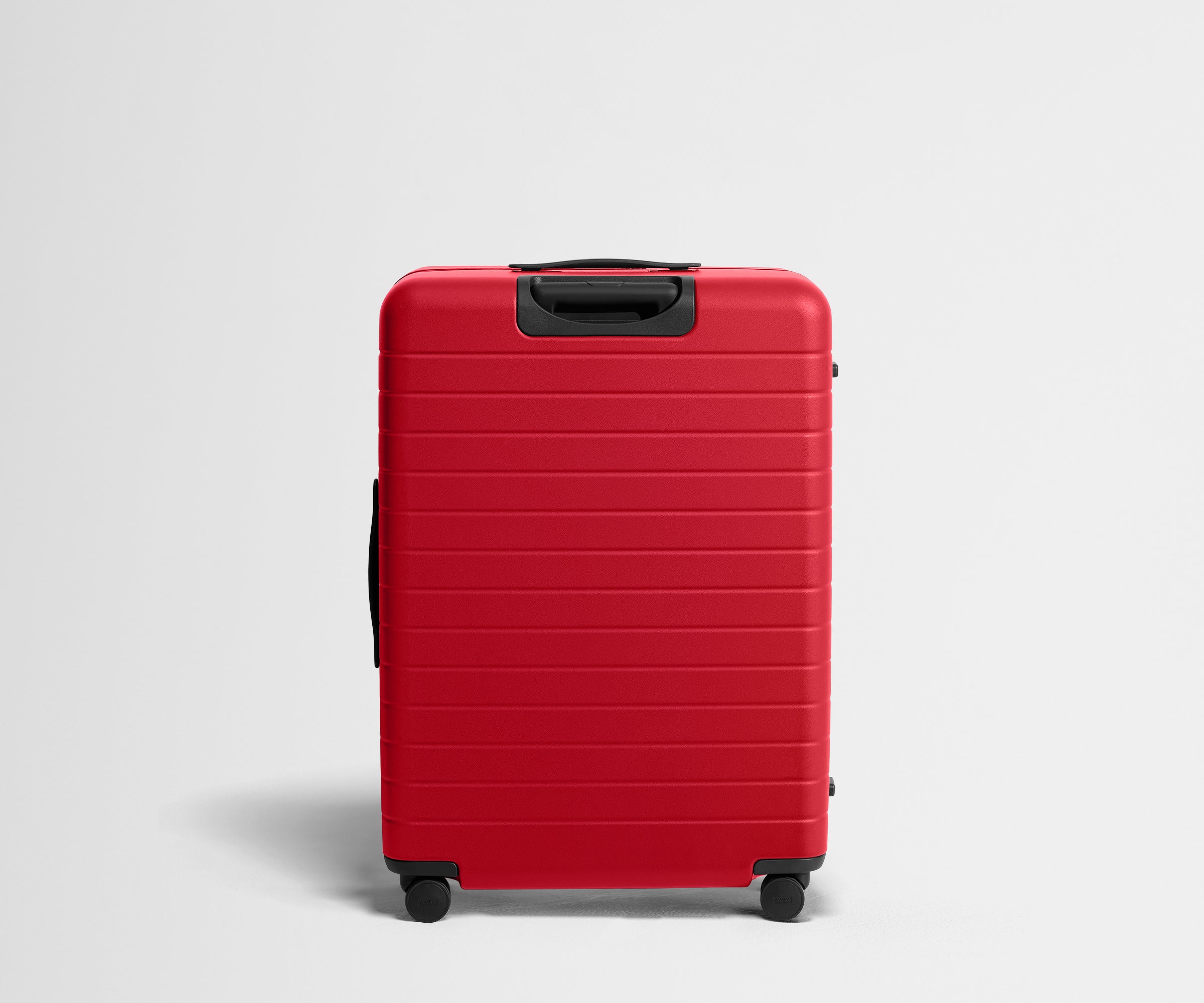 Red suitcase with black handle and wheels on a light gray background