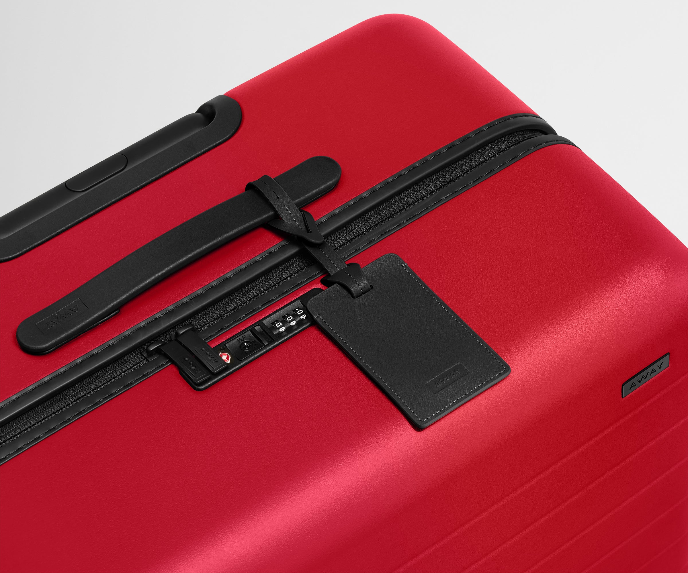 Red suitcase with a black luggage tag on a light gray background