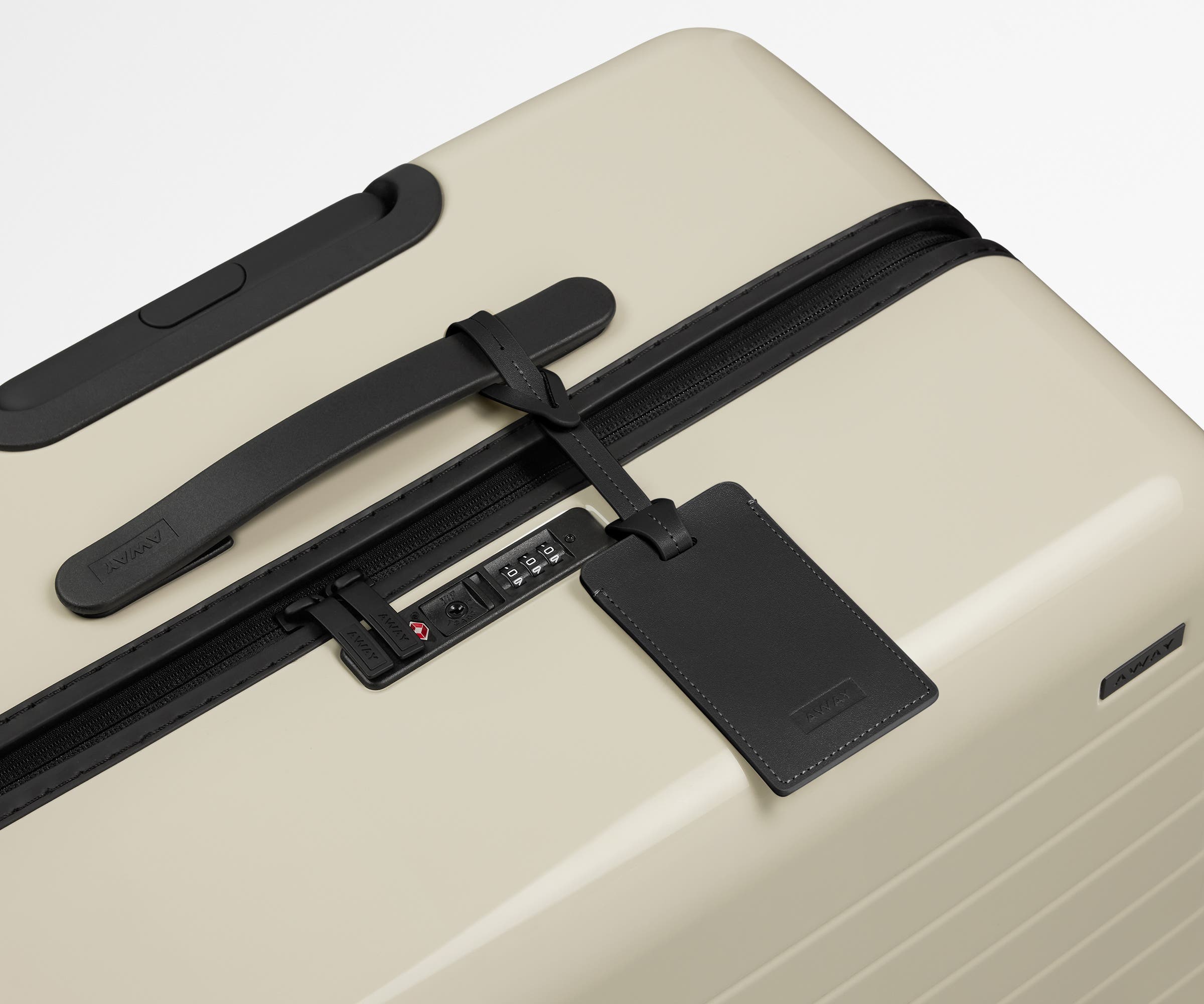 The Large suitcase in Salt White (Gloss) shown shown from above highlighting TSA-approved combination lock and recycled leather luggage tag