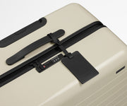 The Medium suitcase in Salt White (Gloss) shown shown from above highlighting TSA-approved combination lock and recycled leather luggage tag
