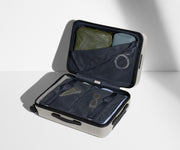 The Carry-On suitcase in Cloud Gray shown open on its side and packed with Away's packing organizers to show capacity and the interior compression system, designed to help you pack more in