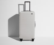 Front product view of The Trunk suitcase in Cloud Gray with raised handle
