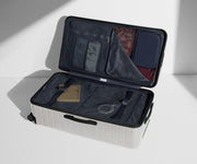 The Trunk suitcase in Cloud Gray shown open on its side and packed with Away's packing organizers to show capacity and the interior compression system, designed to help you pack more in