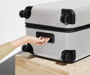 The Trunk suitcase in Cloud Gray shown from below highlighting the underside grab handle