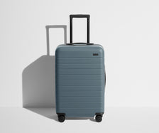 Front product view of The Bigger Carry-On suitcase in Coast Blue with raised handle