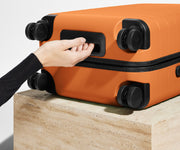 The Carry-On suitcase in Sorbet Orange shown from below highlighting the underside grab handle