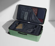 The Trunk suitcase in Sea Green shown open on its side and packed with Away's packing organizers to show capacity and the interior compression system, designed to help you pack more in