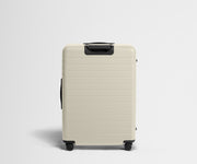 White suitcase with black handle and wheels on a light gray background