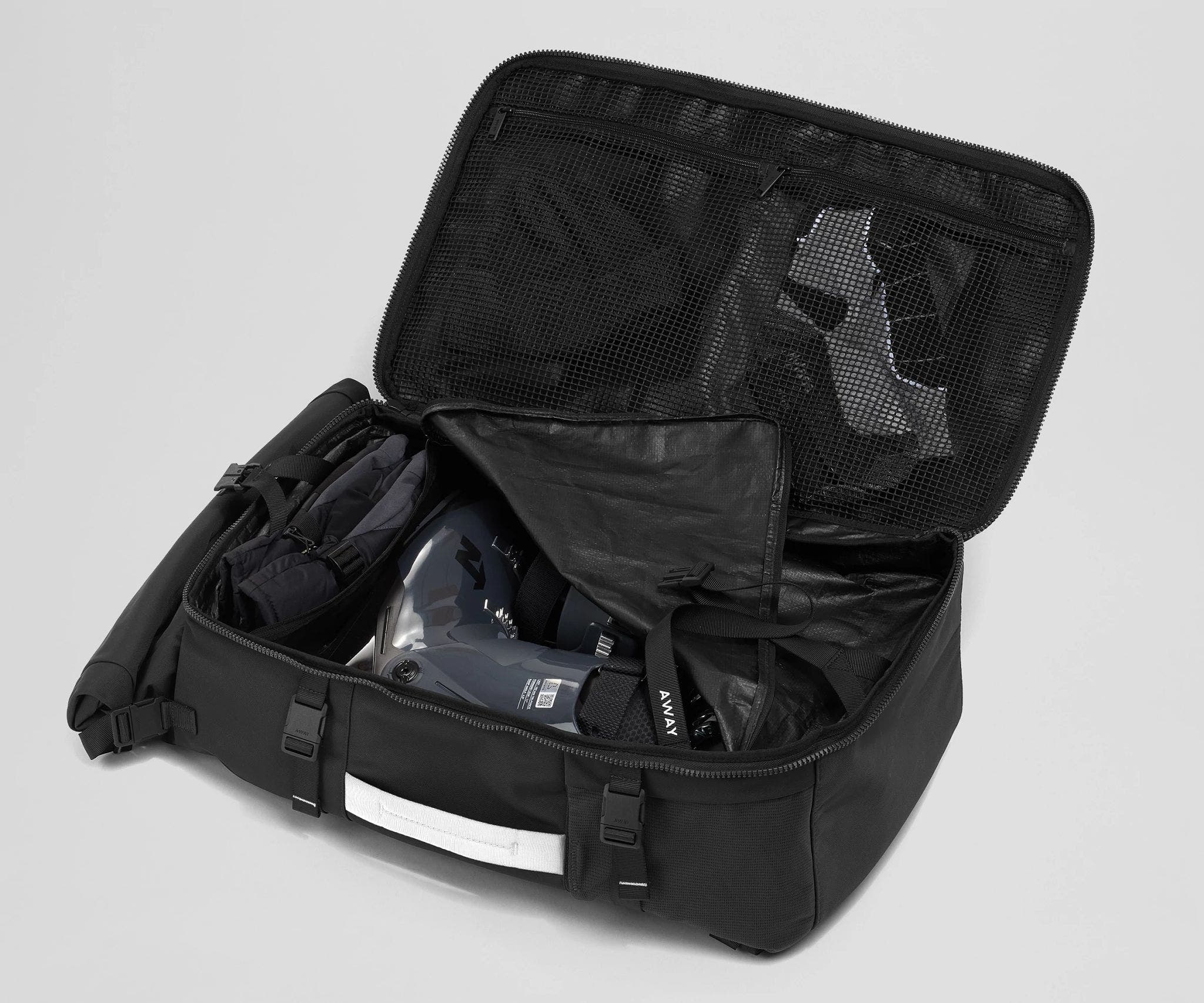 Ski boots packed into the removable boot cube inside the Boot Bag. Winter hat and clothing in the front mesh pockets