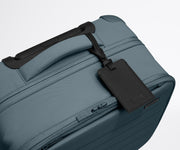 The Softside Compact Carry-On suitcase in Coast Blue shown shown from above highlighting the recycled leather luggage tag