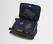 The Softside Bigger Carry-On suitcase in Olive Green shown open on its side and packed with Away's packing organizers to show capacity and the interior compression system, designed to help you pack more in
