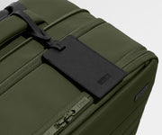 The Softside Carry-On suitcase in Olive Green shown shown from above highlighting the recycled leather luggage tag and expansion feature
