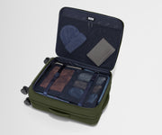 The Softside Medium suitcase in Olive Green shown open on its side and packed with Away's packing organizers to show capacity and the interior compression system, designed to help you pack more in