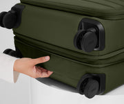 The Softside Medium suitcase in Olive Green shown laying on a surface to highlight the underside grab handle