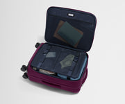 The Softside Bigger Carry-On suitcase in Plum Purple shown open on its side and packed with Away's packing organizers to show capacity and the interior compression system, designed to help you pack more in