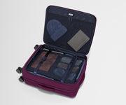 The Softside Medium suitcase in Plum Purple shown open on its side and packed with Away's packing organizers to show capacity and the interior compression system, designed to help you pack more in