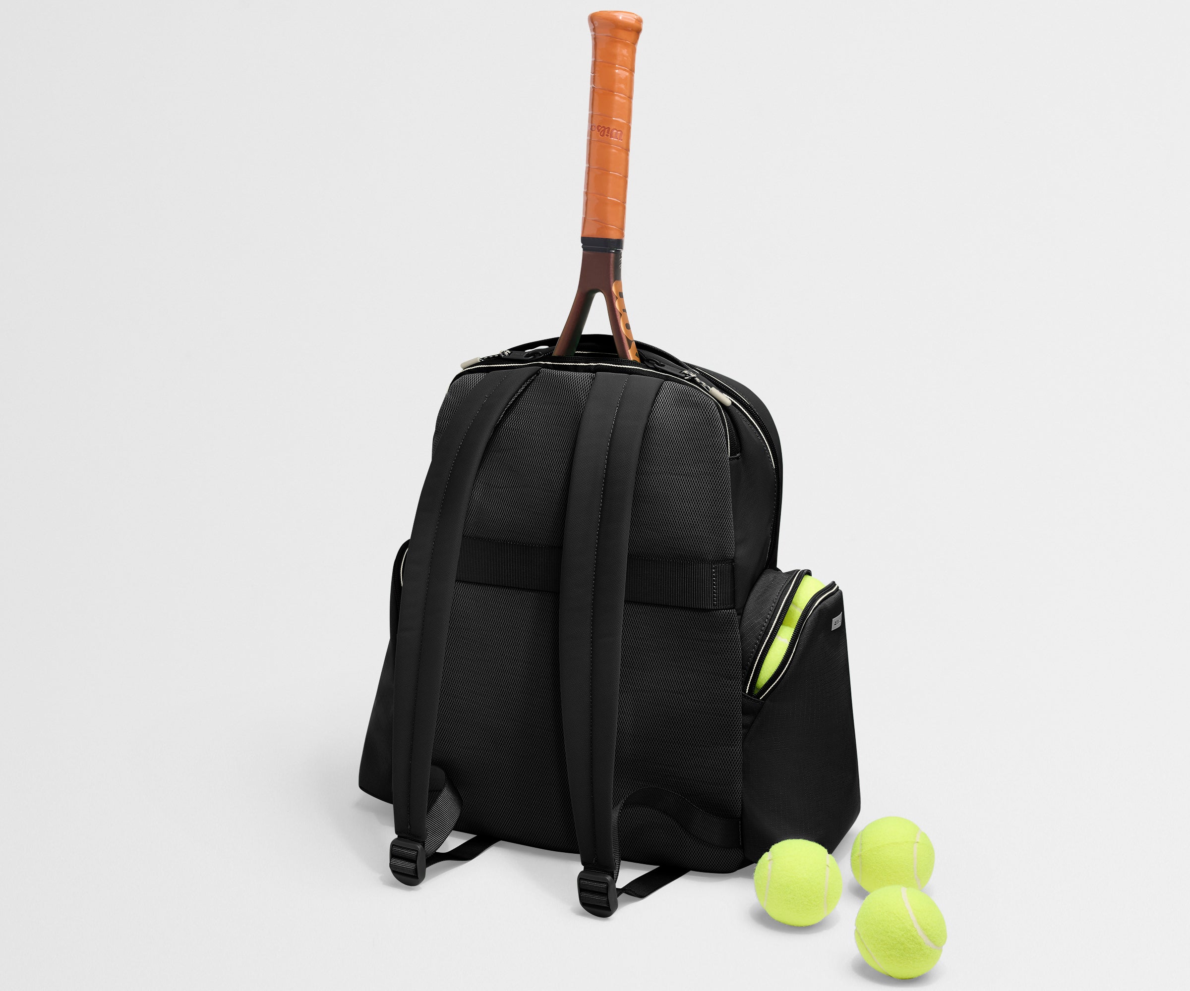 Black backpack with a tennis racket and balls on a light gray background