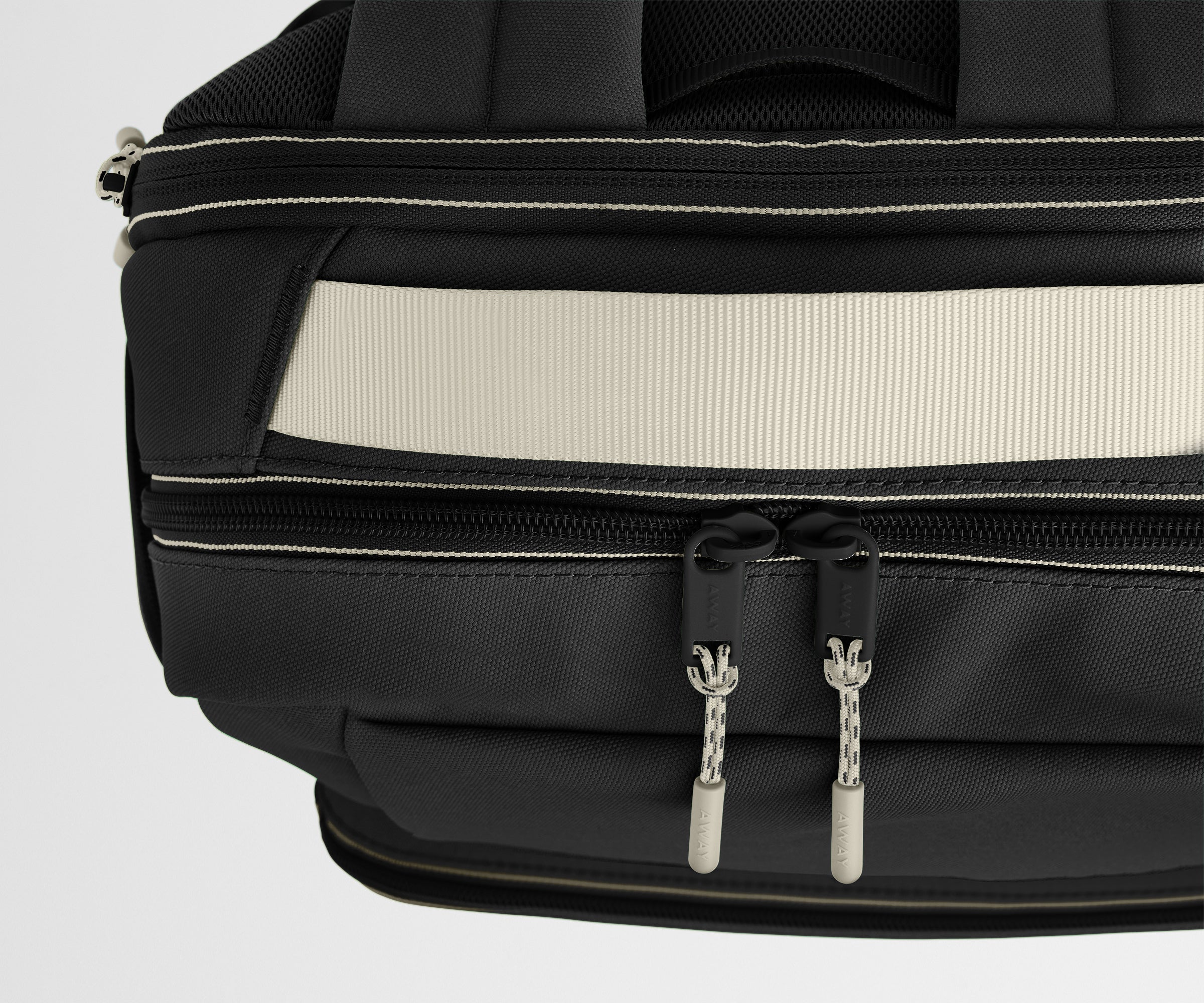 Close-up of a black backpack with beige stitching on a light gray background