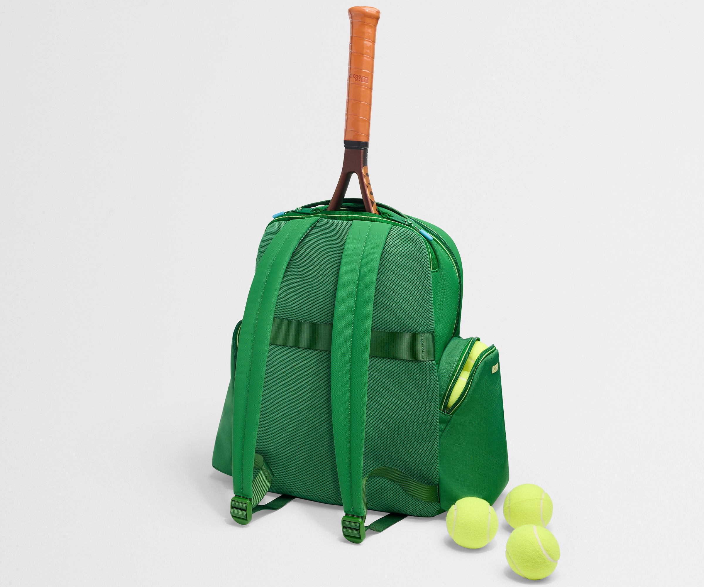 Green backpack with a tennis racket and balls on a light gray background