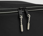 Close-up of a black shoe cube with zippers on a gray background