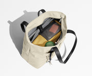 Tote bag packed with a laptop, water bottle, travel pouch, and sweater. A key is attached to the hidden key leash